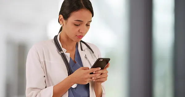 A doctor using a secure texting app to ensure compliance during an emergency situation