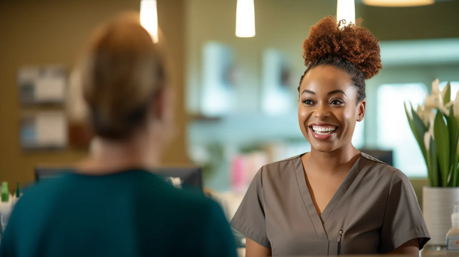 A African american female nurse is greeting a patient at the front desk of a clinic and smiling.
