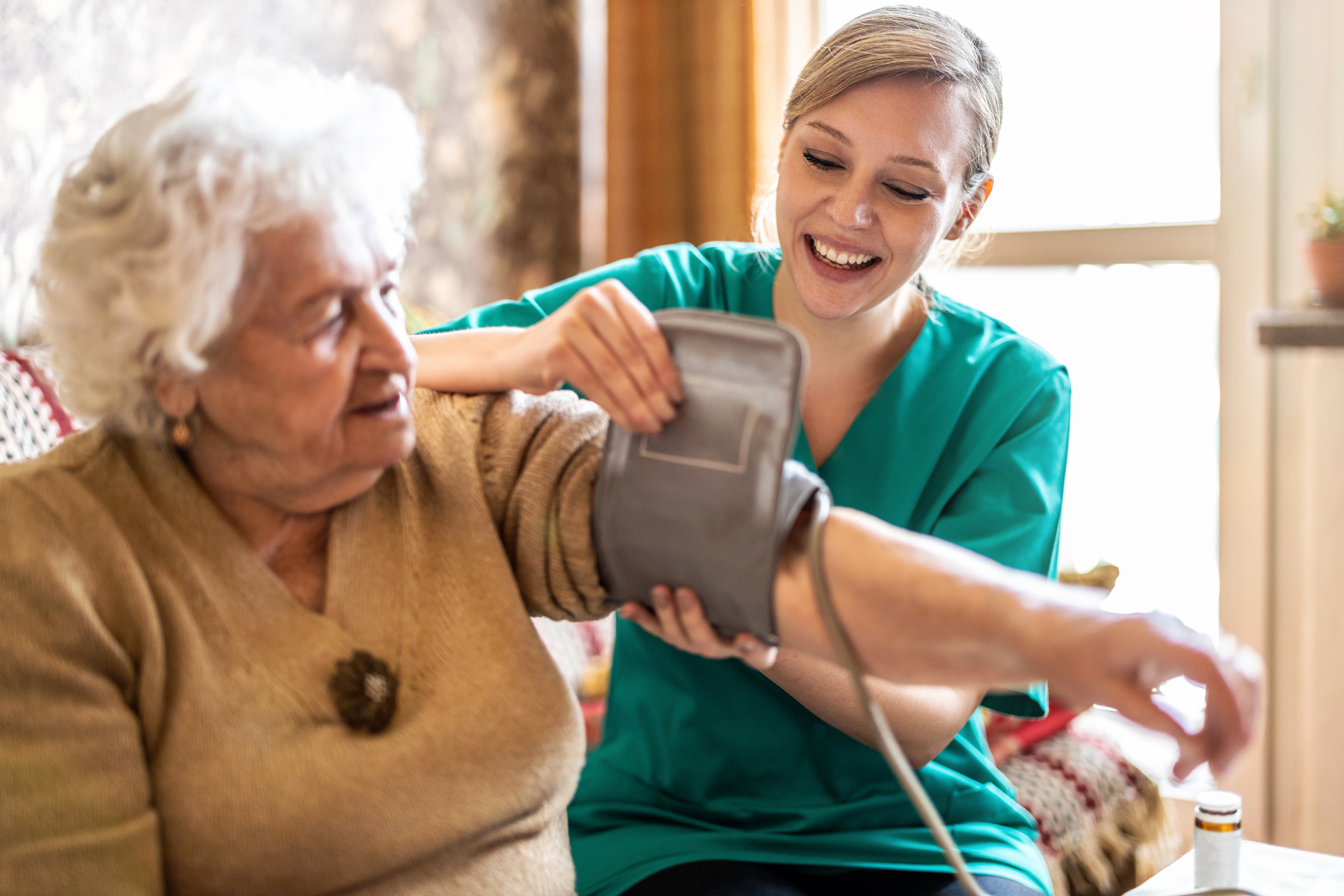 A nurse putting a blood pressure cuff on a elderly woman as apart of her basic home health check-in.