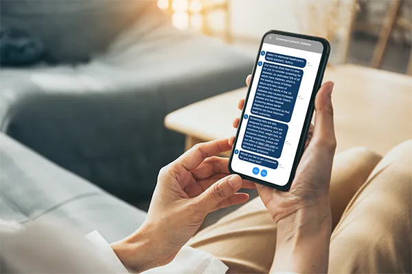 A person seated on a sofa reading a diabetes screening outreach chat from their health system on a phone